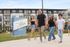 Bright and inviting apartment community of Atlas Eastside with a group of friends joyfully walking in front, showcasing modern living in a vibrant neighborhood.