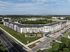 Stunning aerial view of a modern apartment complex, beautifully landscaped with lush greenery, a central pool, and ample parking spaces.