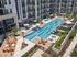Luxurious apartment complex with a stunning pool area, featuring stylish loungers, umbrellas, and vibrant seating for relaxation and entertainment.