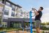 Modern apartment complex with ample green landscaping and a resident exercising on outdoor fitness equipment, highlighting active lifestyle amenities.