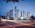 Modern apartment complex with striking architecture, illuminated at dusk, set against a vibrant cityscape.