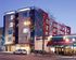 Modern urban apartment complex with vibrant exterior next to a cozy caf&eacute;, ideal for city living.