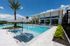 Luxurious outdoor pool area featuring sleek lounge chairs, elegant palm trees, and a modern building with expansive windows.