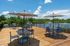 Inviting wooden terrace with chic striped umbrellas and modern outdoor seating overlooking a serene lake view surrounded by lush greenery.