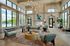 Inviting and spacious living area with elegant decor, high ceilings, and large windows offering abundant natural light and a scenic view of the pool.