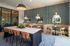Chic and modern communal area featuring a large dining table with stylish chairs, cozy booth seating, and elegant pendant lighting, perfect for social gatherings.