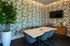 Chic meeting room with tropical foliage wallpaper, a sleek marble table, and modern decor, ideal for creative gatherings.