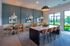 Contemporary dining area with elegant pendant lighting, stylish seating, and large windows offering lush greenery views.