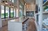 Spacious modern kitchen with high ceilings, a large central island with vibrant orange bar stools, and expansive windows offering scenic views.