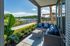 Charming outdoor patio with cozy seating and vibrant cushions, overlooking a serene lake with lush greenery, perfect for relaxation and entertaining.