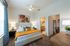 Elegant bedroom featuring a plush bed with vibrant pillows, modern artwork, and a seamless connection to a chic en-suite bathroom.
