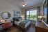 Inviting bedroom with natural light, modern decor, and serene outdoor view featuring stylish furnishings and vibrant greenery.