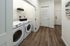 Modern laundry area with sleek washer and dryer, bright walls, and stylish wood flooring.