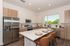 Modern kitchen design featuring sleek stainless steel appliances, elegant white countertops, and stylish wooden cabinetry, enhanced by abundant natural light.