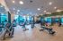 Spacious and modern fitness center with large windows, fully equipped with treadmills, weight benches, and free weights offering a bright workout environment.