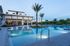 Luxurious apartment complex featuring a serene pool area with stylish loungers and lush palm trees for ultimate relaxation.