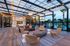 Chic outdoor lounge area with modern seating, stylish lighting, and pool view under a contemporary pergola.