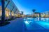 Luxurious apartment complex with a stunning illuminated pool area and modern architectural design, perfect for evening relaxation.