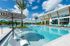 Luxurious apartment pool area featuring sparkling blue water, stylish lounge chairs, and elegant umbrellas under a sunny sky.