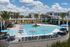 Luxurious apartment complex featuring a stunning outdoor pool area with stylish loungers, vibrant umbrellas, and lush palm trees against a backdrop of modern architecture.