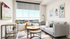 Bright and stylish living room with a panoramic window view, chic gray sofa, modern art, and a cozy armchair.