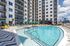 Luxurious apartment complex with a sparkling pool, stylish lounge chairs, and captivating city views.