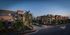 Elegant apartment complex surrounded by lush palm trees and illuminated by a serene evening glow, offering a luxurious and tranquil living environment.