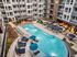 Luxurious apartment complex with a stunning outdoor pool, stylish lounge chairs, modern cabanas, and vibrant landscaping, creating a perfect urban oasis.