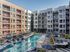 Modern apartment complex with large swimming pool, sun loungers, and outdoor seating, highlighting urban luxury living.