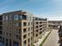 Modern apartment building with expansive windows, rooftop amenities, and scenic views of the surrounding area on a sunny day.