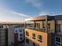 Modern high-rise apartment with expansive glass balcony offering stunning sunset views over the cityscape.