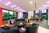 Vibrant modern lounge with stylish seating, colorful lighting, and floor-to-ceiling windows creating a chic and inviting atmosphere.
