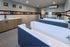 Modern pet grooming room featuring sleek countertops and dual bathing stations, accented by playful dog-themed wall art.