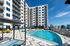Luxurious apartment complex showcasing a sparkling pool, modern sun deck, and elegant high-rise architecture with city skyline views.