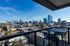 Breathtaking cityscape view from a modern apartment balcony, showcasing vibrant urban allure with contemporary high-rises under a clear blue sky.
