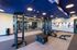 Modern fitness center with sleek exercise equipment, vibrant artwork, and bright blue ceilings, ideal for workouts and relaxation.