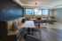 Chic communal dining area with modern decor and vibrant booth seating, offering a spacious and inviting atmosphere with cityscape views.