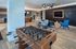 Modern communal lounge featuring a sleek foosball table, contemporary seating, and stylish wall art, perfect for relaxation and entertainment.