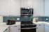 Modern kitchen with sleek white cabinets, stainless steel appliances, and stylish blue tile backsplash, creating a fresh and inviting atmosphere.