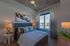 Elegant bedroom with modern decor, featuring a plush bed, stylish lamps, and a large window with a city view.
