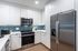 Modern kitchen with sleek stainless steel appliances, stylish white cabinetry, and a contemporary blue tiled backsplash.