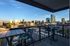 Elegant urban balcony with modern furniture, offering breathtaking sunset views of the city skyline.