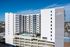 Modern high-rise residential building with spacious balconies overlooking a stylish outdoor pool and sun deck.