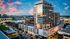 Captivating cityscape featuring a luxurious high-rise apartment building with modern glass architecture, surrounded by urban amenities and vibrant city lights at sunset.