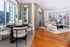 Modern apartment living room with elegant decor, featuring floor-to-ceiling windows, chic furniture, abstract wall art, and a cozy dining area with a city view.