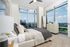 Luxurious bedroom with modern decor, featuring a cozy bed, stylish dresser, floor-length windows offering breathtaking scenic views, and natural sunlight.