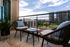 Chic apartment balcony with modern seating, vibrant greenery, and a stunning urban skyline view.