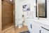 Modern bathroom with elegant glass shower, sleek white vanity, and contemporary artwork.