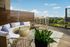 Chic rooftop patio with elegant wicker seating, lush greenery, and stunning cityscape views.