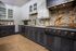 Modern kitchen with sleek black cabinetry, elegant marble backsplash, and luxurious gold accents.
